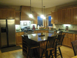 A kitchen with wood cabinets and floors with an island