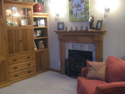 A gray tiled fireplace with a custom wooden mantle